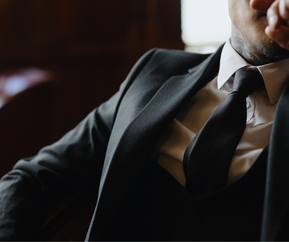 closeup of man wearing black three-piece suit, white shirt, and black tie